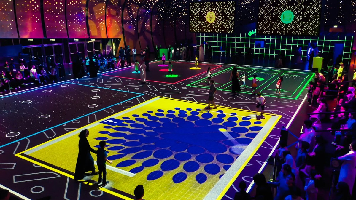 Moment Factory's larger-than-life video games experience Augmented Games has been programmed for Illuminate Adelaide 2026. People watch on from the sides as participants step onto the boards of immersive, large-scale video games.