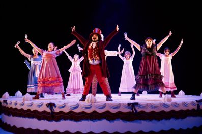Bloomshed's Pride and Prejudice at Malthouse Theatre, 2026. Characters dressed in exaggerated and colourful versions of Regency era costumes celebrate atop a giant, decorated cake.