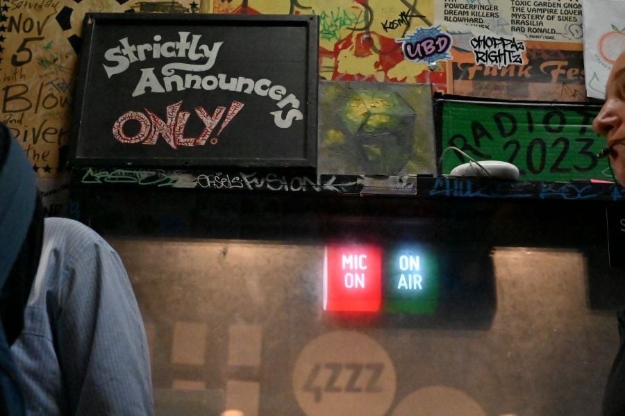 Brisbane-based community radio station 4ZZZ. Illuminated buttons read 'MIC ON' and 'ON AIR'.