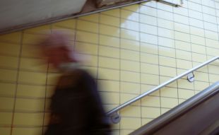 A blurred figure hurries down a tiled staircase, perhaps to catch a train. arts sector appointments