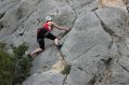 A female rock climber, photographed from below as she ascends a sheer rock face. arts sector appointments