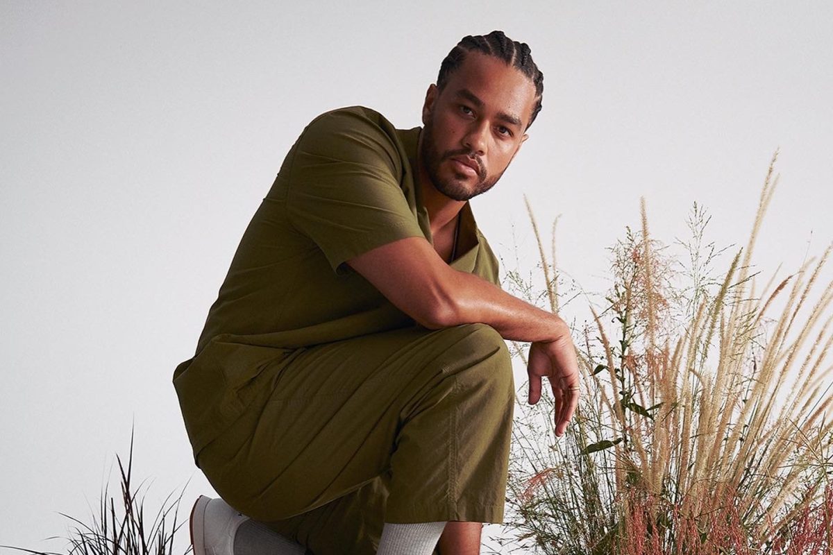 Poetry Month 2026 international guest Jericho Brown (US). The photo shows a Black American man standing in a half-crouched position with tall grass growing behind him.