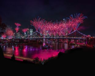 Riverfire by Australian Retirement Trust returns for Brisbane Festival 2026. Fireworks light up Brisbane's skyline and bridges at night, and are reflected in the Brisbane River.