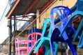 Plastic chairs hang from hooks in an outdoor market, looking as if they're piled atop each other or about to break free. arts sector appointments