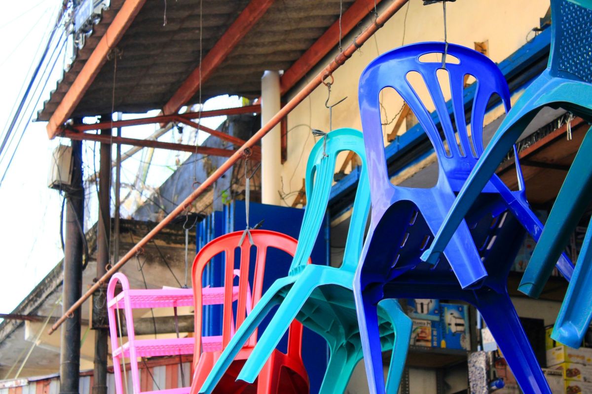 Plastic chairs hang from hooks in an outdoor market, looking as if they're piled atop each other or about to break free. arts sector appointments