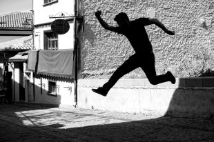 A leaping figure is silhouetted like a shadow against a brightly lit wall in this stark black and white image. arts sector appointments
