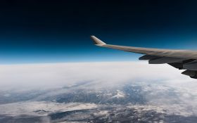 A photograph by Daniel Olah taken through an aeroplane's window at high altitude,showing part of the plane's wing, the horizon, and the cloud-covered planet below. arts sector appointments