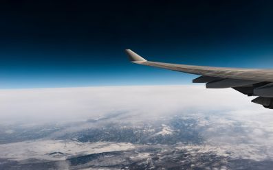 A photograph by Daniel Olah taken through an aeroplane's window at high altitude,showing part of the plane's wing, the horizon, and the cloud-covered planet below. arts sector appointments