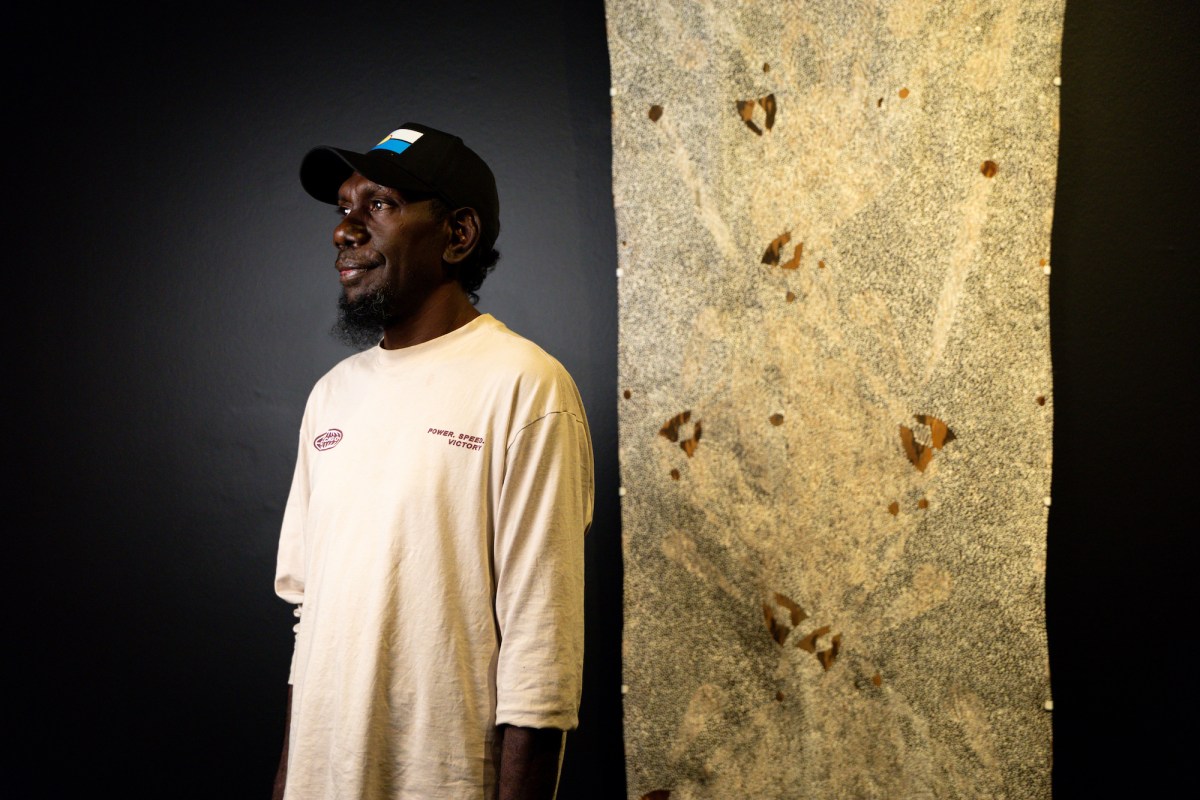 Barayuwa Munuŋgurr with his work, ‘The hidden reef at Yarrinya’ 2025. Courtesy of the artist and Buku Larrŋgay Mulka. Photo: Charlie Bliss.