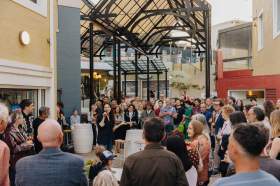 new arts precinct: a photogrpah of a small outdoor piazza space packed with people listening to an opening address to an arts event.