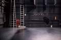 performing arts cost increases: a photo of a theatre's empty stage showing a ladder against its back wall and some equipment items at the back of the stage.